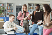 Four youth gathered around talking and showing their work to each other