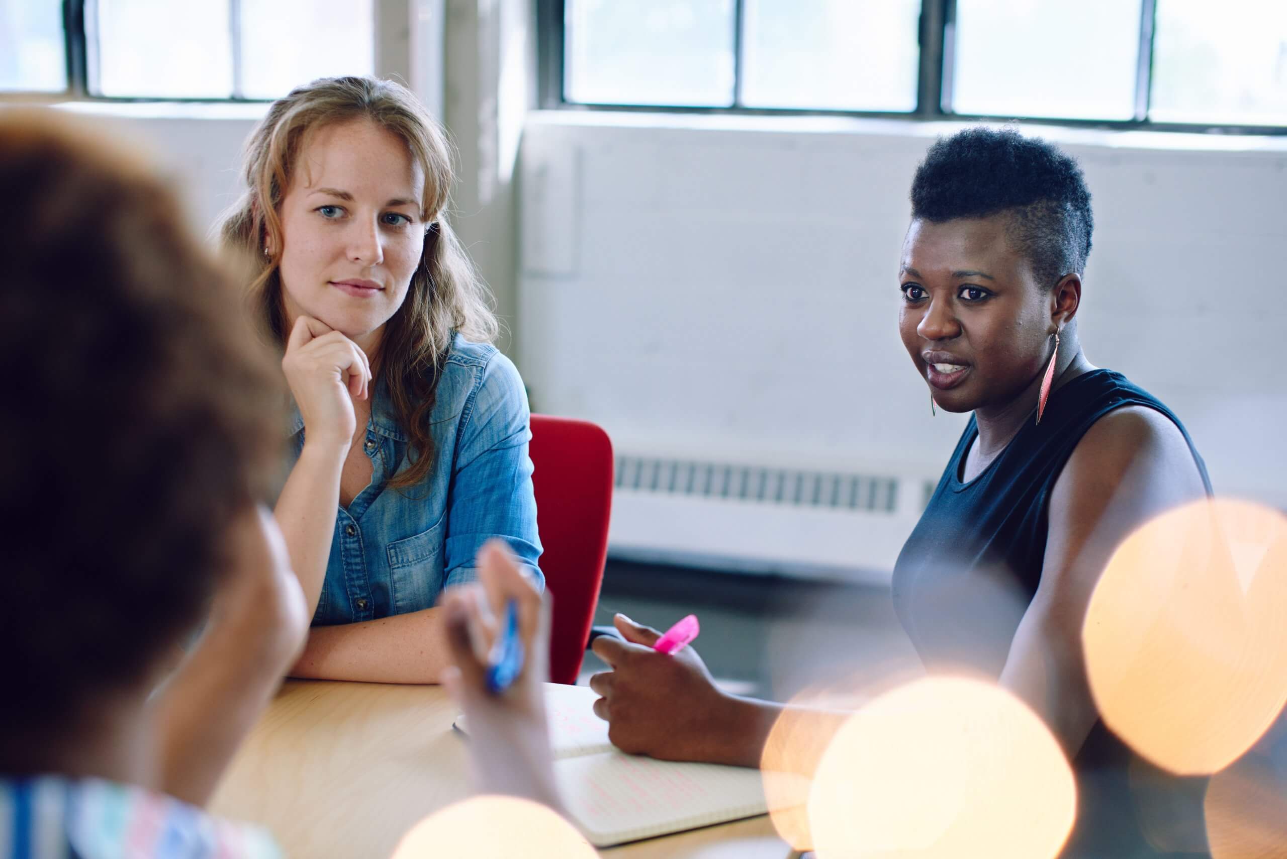Two women in a group listening to others speak